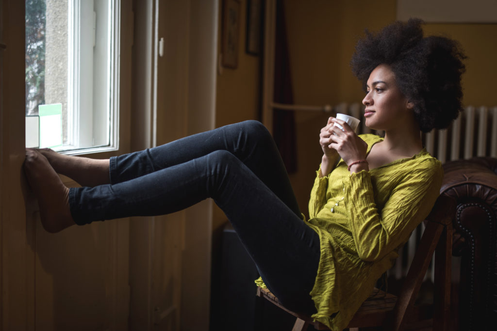 Young African American woman enjoying in coffee time at home.