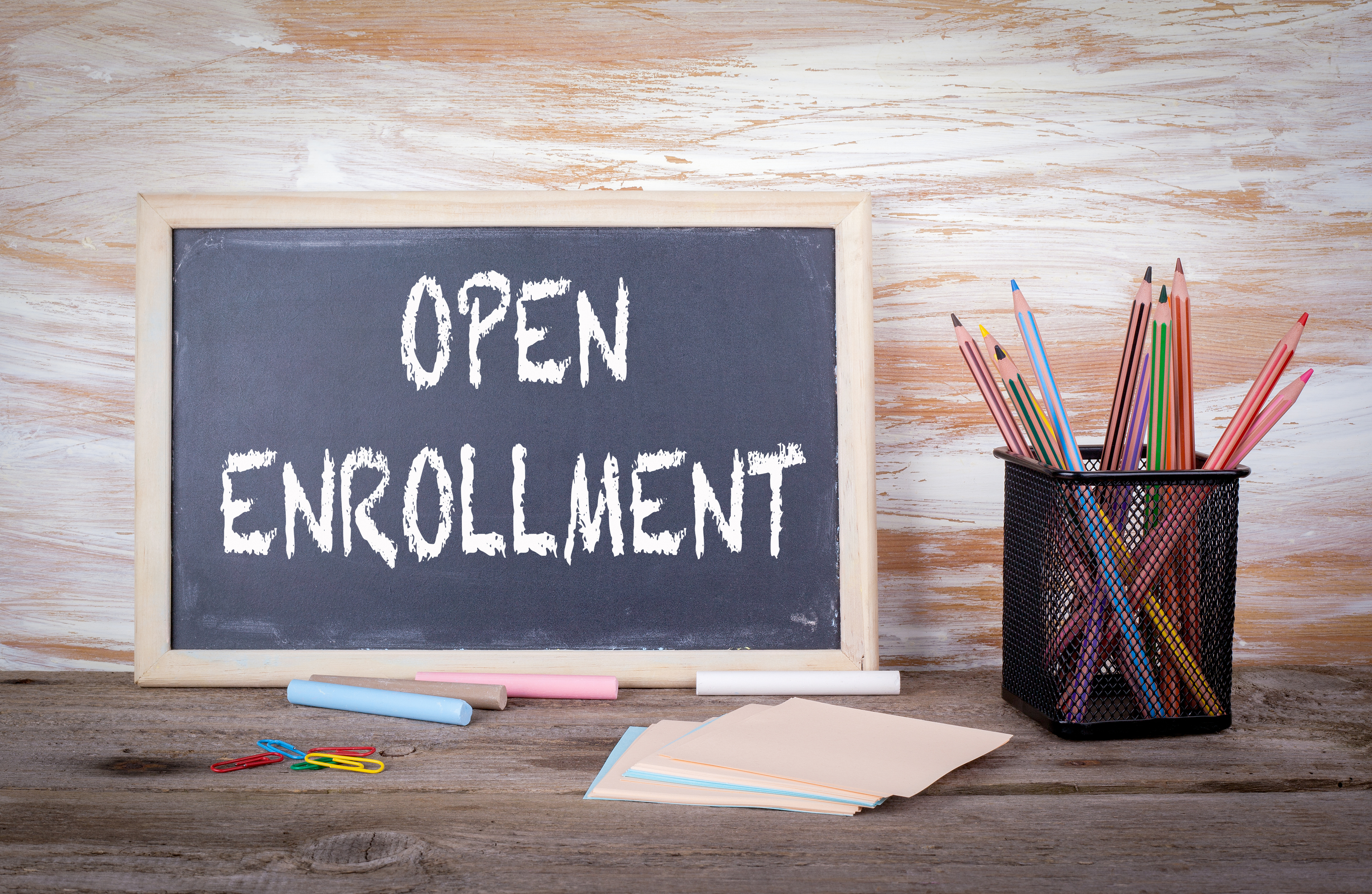Open Enrollment text on a blackboard. Old wooden table with texture