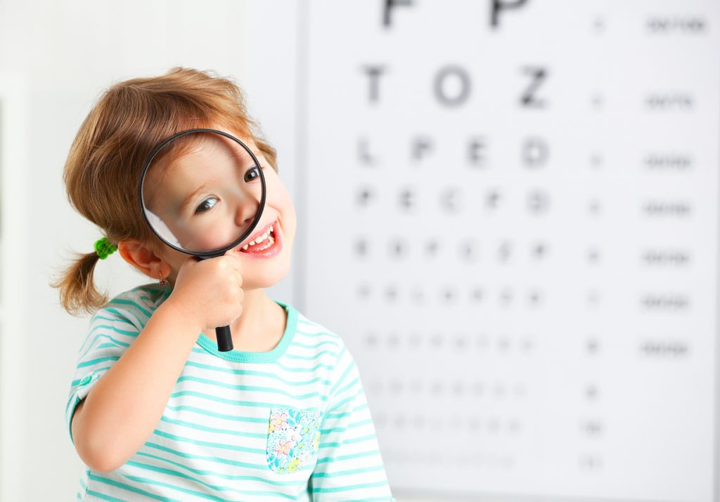 concept vision testing. child girl with a magnifying glass