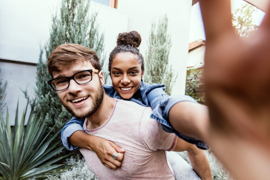 millennials need health insurance - Boyfriend and girlfriend taking selfie, piggy back ride