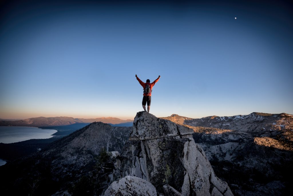 Image of a man triumphantly summiting a mountain