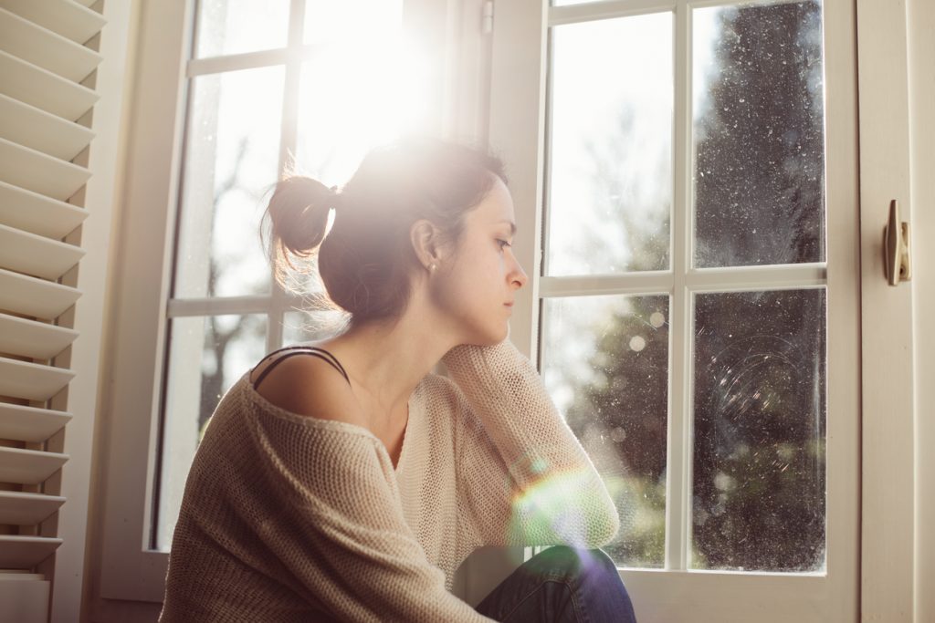 Unhappy housewife sitting near the window - stress awareness month